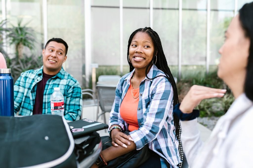 A group of diverse college students having a conversation outside in a relaxed campus setting.